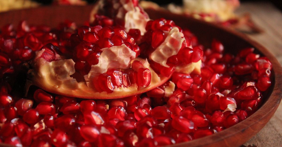 Vibrant close-up of fresh pomegranate seeds in a wooden bowl capturing their vivid color and texture.